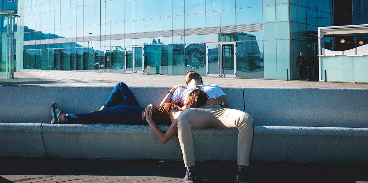 casal a dormir num banco de pedra