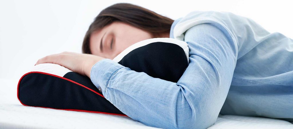 Que almofada me convém para a dor cervical rapariga com dor cervical a dormir de barriga para baixo, com uma almofada cervical