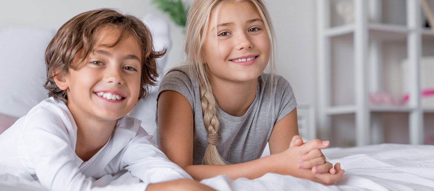 um menino e uma menina deitados na cama a sorrir