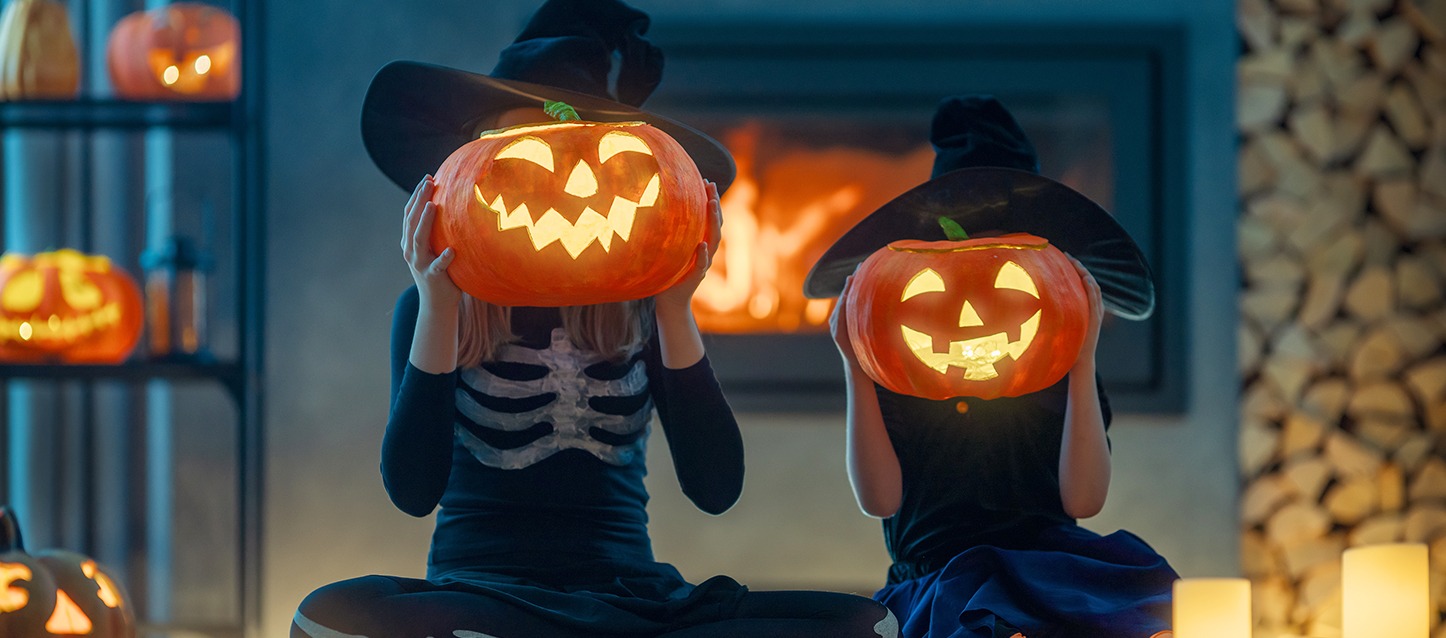 dois meninos disfarçados no Halloween a segurar uma abóbora de Halloween à altura da cara